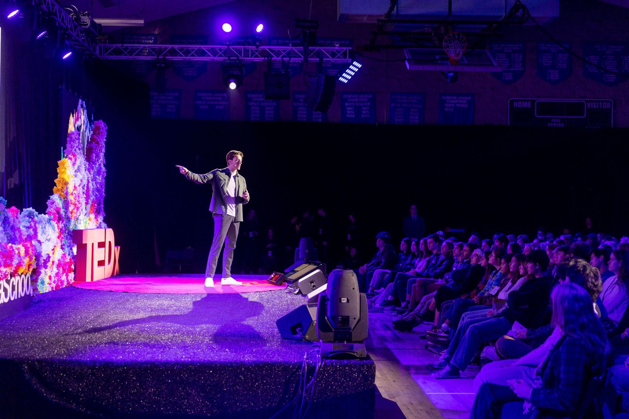 Dino Ambrosi speaking on the TEDx stage to a full audience of students