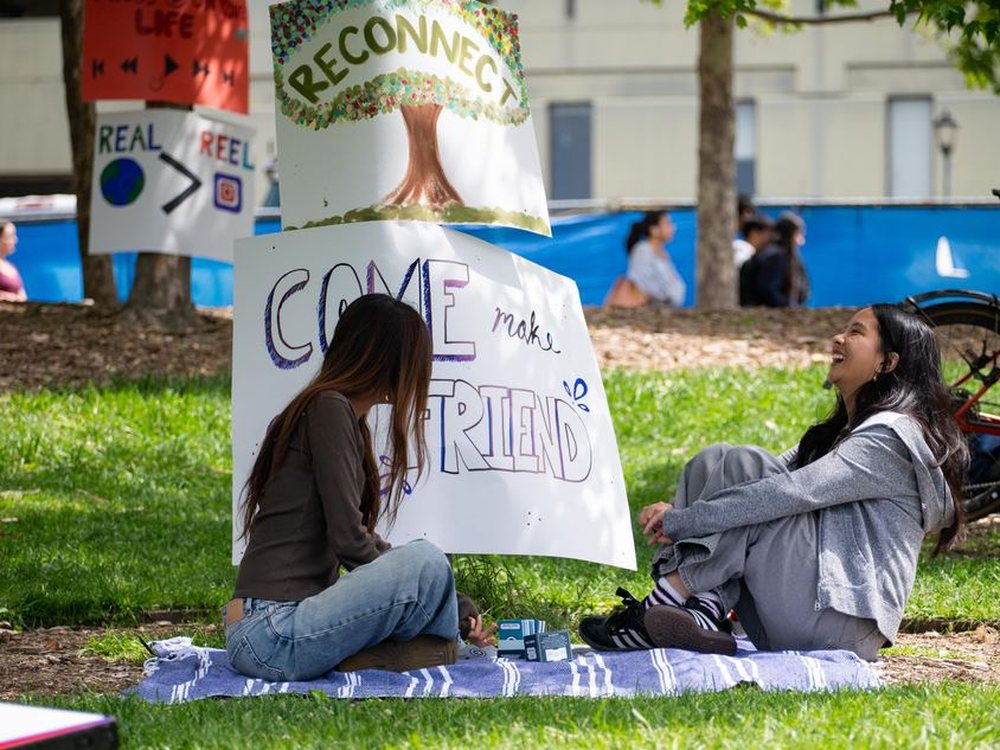 Two Project Reboot students sitting and talking on the lawn.